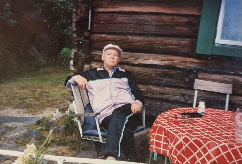 Arne vilar i en solstol framför Wahmans stuga